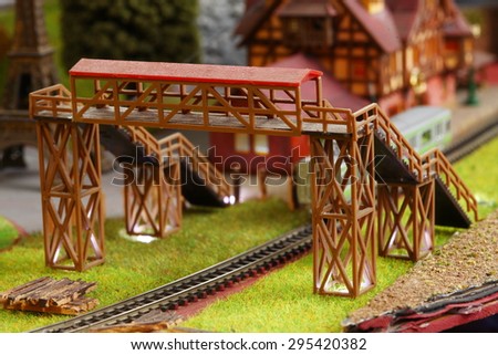 Old and dirty plastic model of pedestrian bridge across model railway track represent the model train toy equipment concept related idea.