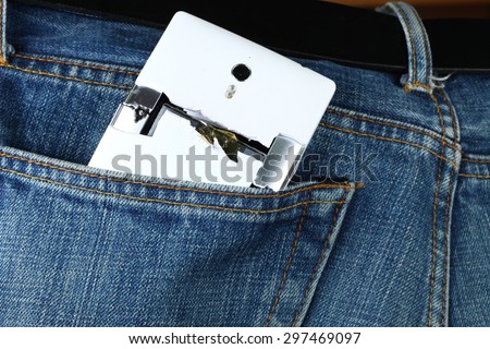Blue denim jeans in dark color in the scene present the old denim look at the back pocket part with broken mobile phone inside.