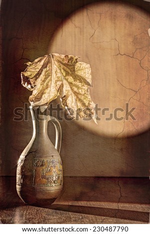 Still life in the style of grunge. Dry leaf in a ceramic jug