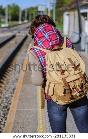 Girl with backpack waits train on train station