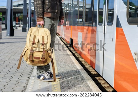 Young tourist man on railway platform near train doors