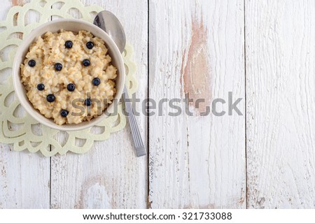 Oatmeal porridge for breakfast on white wooden background
