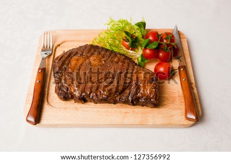 Appetizing stake with tomatoes on a wooden plate