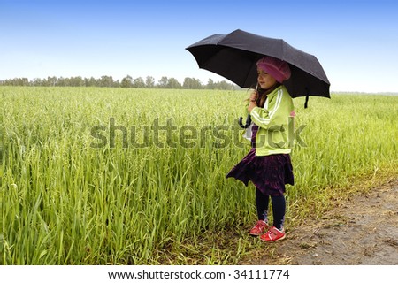 The little girl on a farmer field with an umbrella