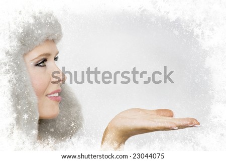 Close up portrait of a beautiful smiling girl in fur hat and opened palm with a space for your text