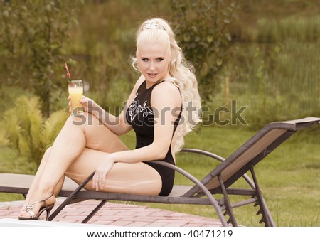 Young beautiful woman with curly blond hair holding glass with orange juse