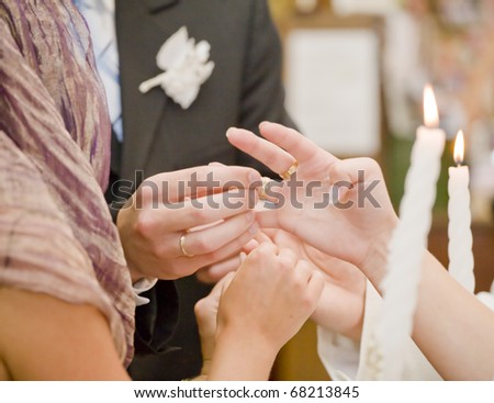 Fiance is putting on wedding ring on bride\'s finger