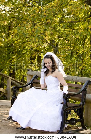 A bride sitting on a bench adjusts her hair