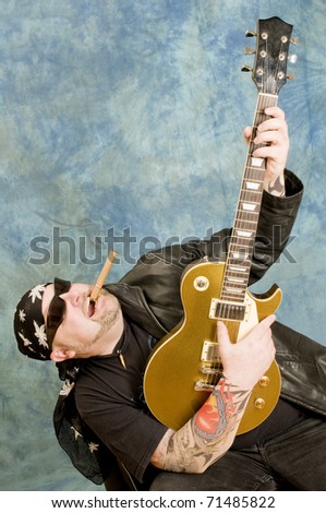 Rock guitarist is playing against the blue background