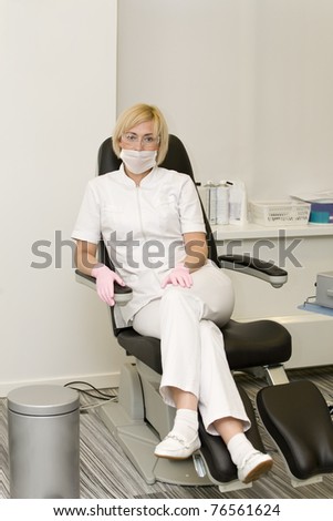 Nurse in respiratory bandage is sitting on pedicure chair