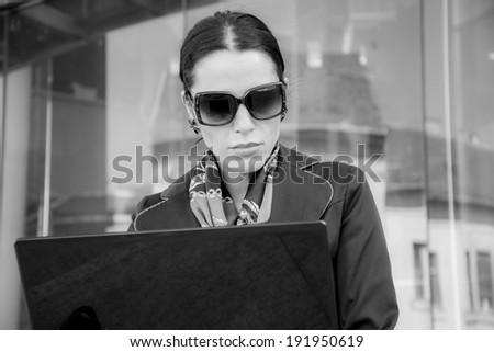 Business woman with a computer outside an office building in black and white