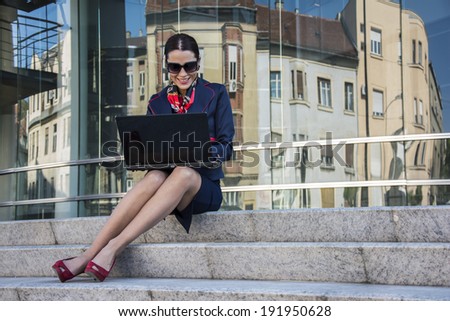 Business woman with a computer outside an office building