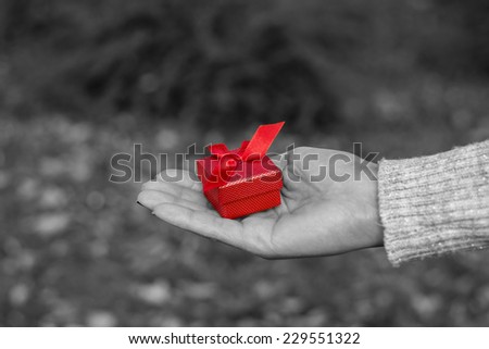Woman holding a red gift box in black and white effect