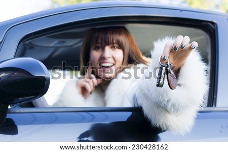 Beautiful woman in white fur coat holding car keys from an open window