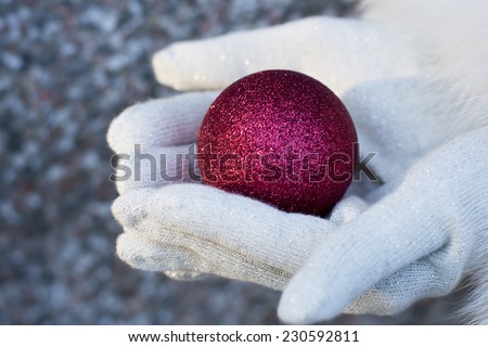Woman holding a red shiny Christmas tree bauble wearing red gloves