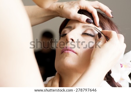 Bride is getting professional make up for her wedding day,while groom watching.