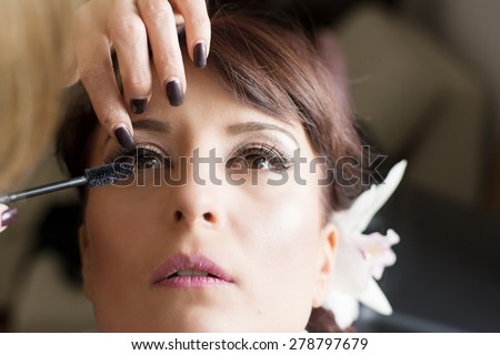 Bride is getting professional make up for her wedding day,putting on mascara.