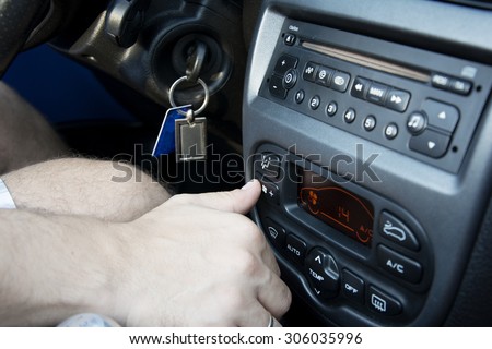 Driver setting the air condition in car because of the high summer temperatures