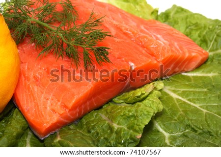 Fresh salmon fillet with lemon and dill on lettuce leaves