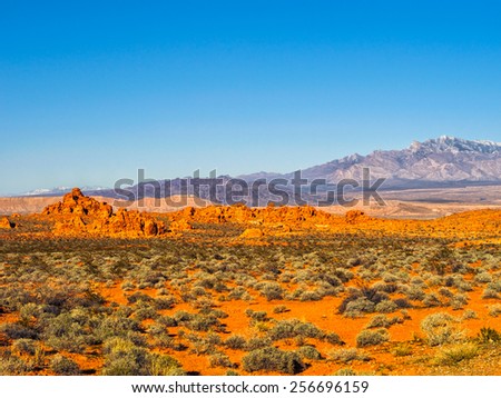 Red rock formations in Valley of Fire State Park, Nevada, USA, with snow-covered mountains in the background, clear blue sky and copy space.. Valley of Fire is in the Mojave Desert in southern Nevada.