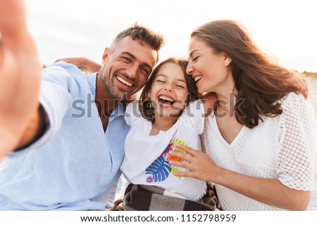 Image of young happy family outdoors at the beach take a selfie by camera.