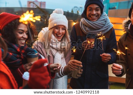 Image of a happy young friends talking with each other drinking coffee outdoors winter concept.