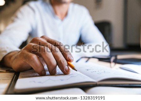 Close up of a busy business man working with documents late at night at the office