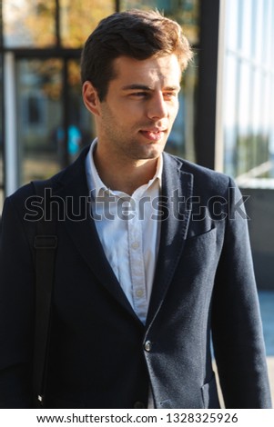 Confident young business man carrying bag, walking outdoors