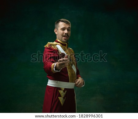 Casino winner. Young man in suit as Nicholas II isolated on dark green background. Retro style, comparison of eras concept. Beautiful male model like historical character, monarch, old-fashioned.