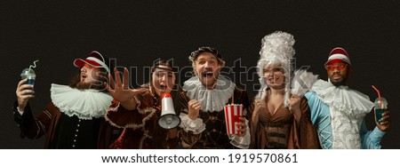 Party, hanging out, cheers. Medieval people as a royalty persons in vintage clothing on dark background. Concept of comparison of eras, modernity and renaissance, baroque style. Creative collage.