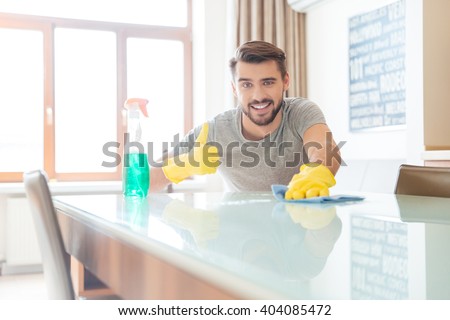 Happy bearded man cleaning his flat and showing thumbs up
