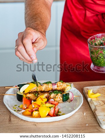 chef making chicken kebab with salad