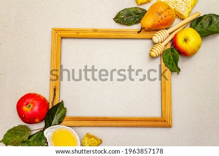 Wooden frame with Rosh Hashanah traditional symbols. Jewish New Year holiday with fresh apples and pears, liquid honey and honeycombs. Light stone concrete background, close up