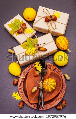 Autumn table setting. Thanksgiving or Halloween concept. Crafted gift boxes, fall decor and black cutlery. Stone concrete background, top view