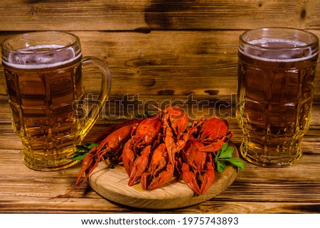 Two glasses of beer and boiled crayfish on rustic wooden table