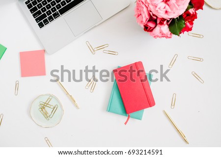 Flat lay home office desk. Female workspace with laptop, pink and red roses bouquet, golden accessories, red and mint diary on white background. Top view feminine background.
