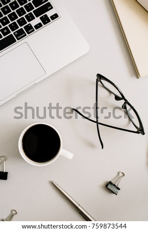 Home office desk with laptop, glasses, coffee mug and stationery on pastel background. Flat lay, top view business concept.