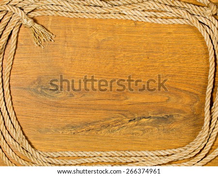 Frame from old rough rope with a knot on a wooden background