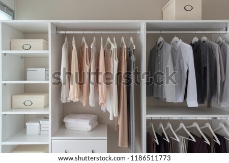 modern closet with clothes hanging on rail, white wooden wardrobe, interior design concept