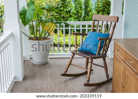 wooden rocking chair on front porch with pillow