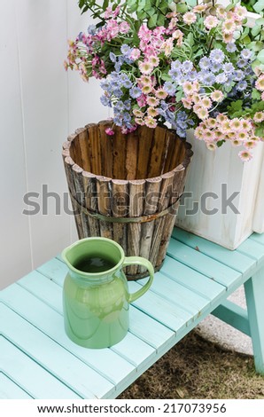 flower on green bench in garden with jar