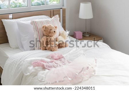 white bedroom with pillows and doll on white bed