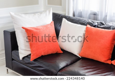 orange and white pillows on modern black sofa in living room