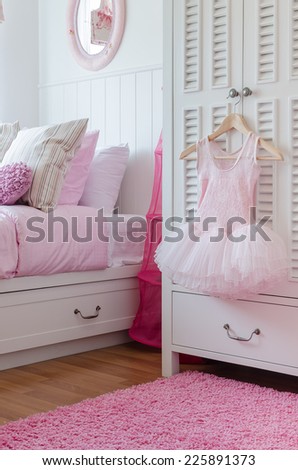 girl\'s pink dress hanging on wardrobe in bedroom at home