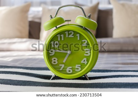 modern green alarm clock on bed at home