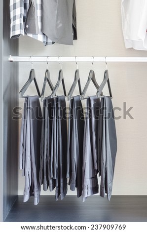 row of black pants hangs in wardrobe at home