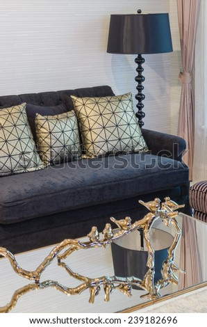 gold pillow on black sofa with black lamp