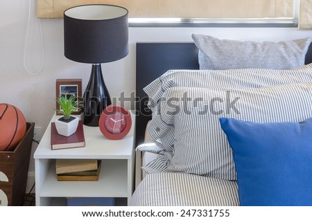 blue pillow on modern bed with black lamp on white table at home