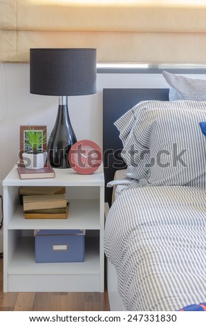 white table with plant in vase on book and black lamp in bedroom at home