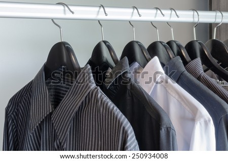 row of black and white shirts hanging in wardrobe